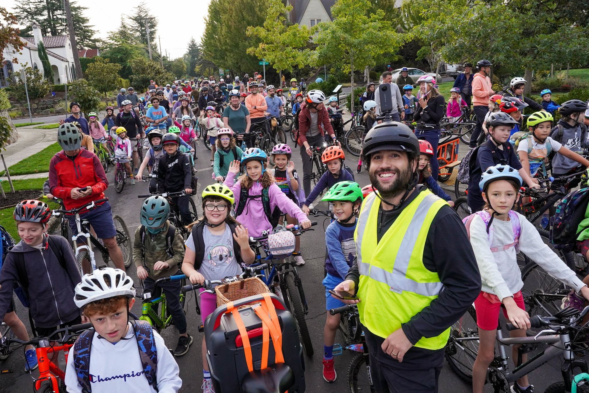 Coach Sam Balto and a crowd of smiling children and families riding Alameda Elementary's bike bus in Portland.