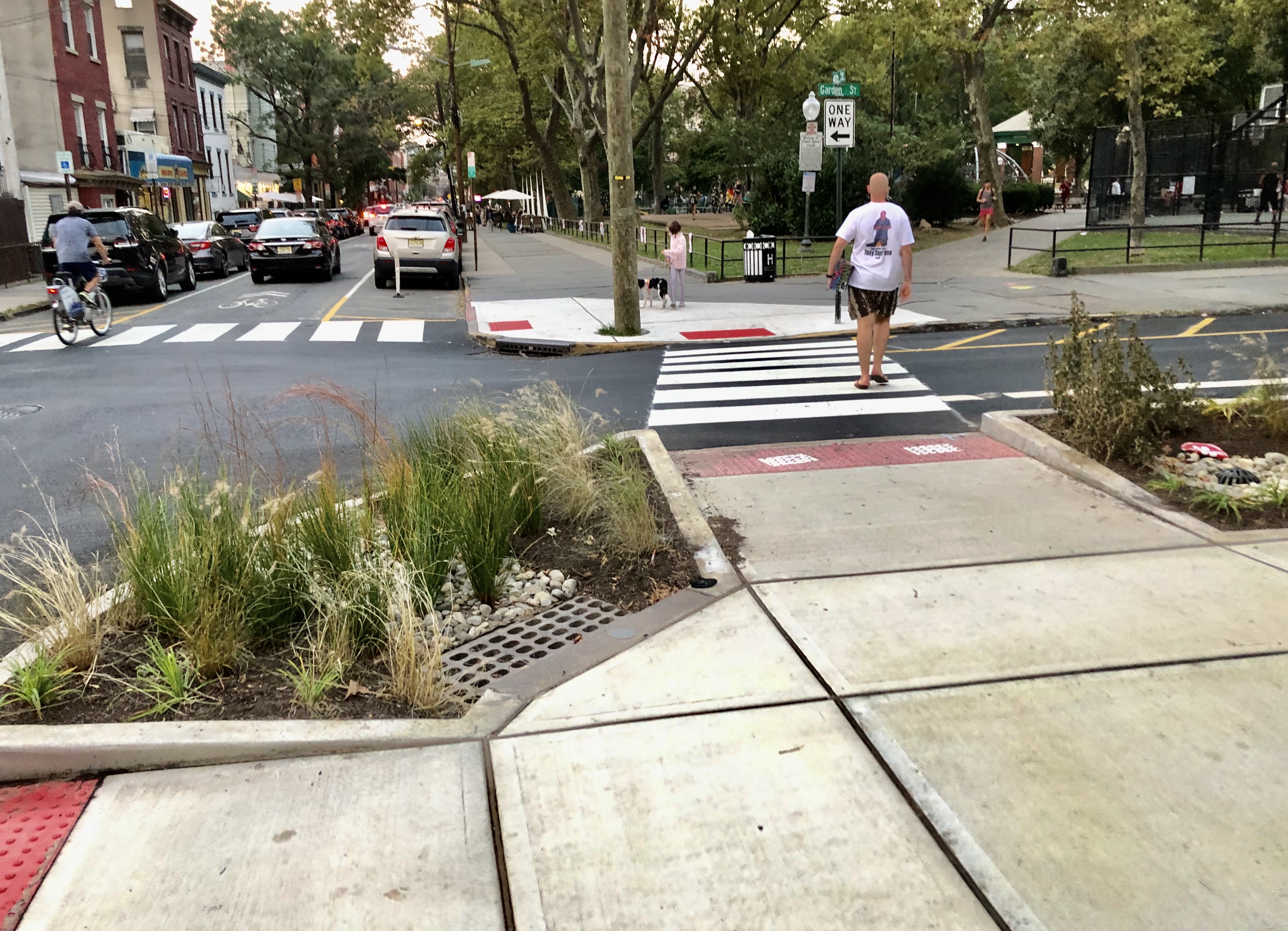 A person crosses between planted curb extensions on Garden Street in Hoboken.
